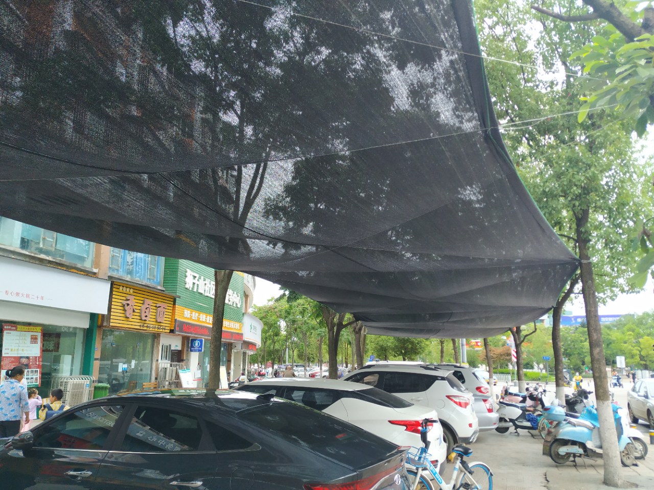 资阳一处人行道公共停车位上出现遮阳网,大家一起来聊聊自己的看法和