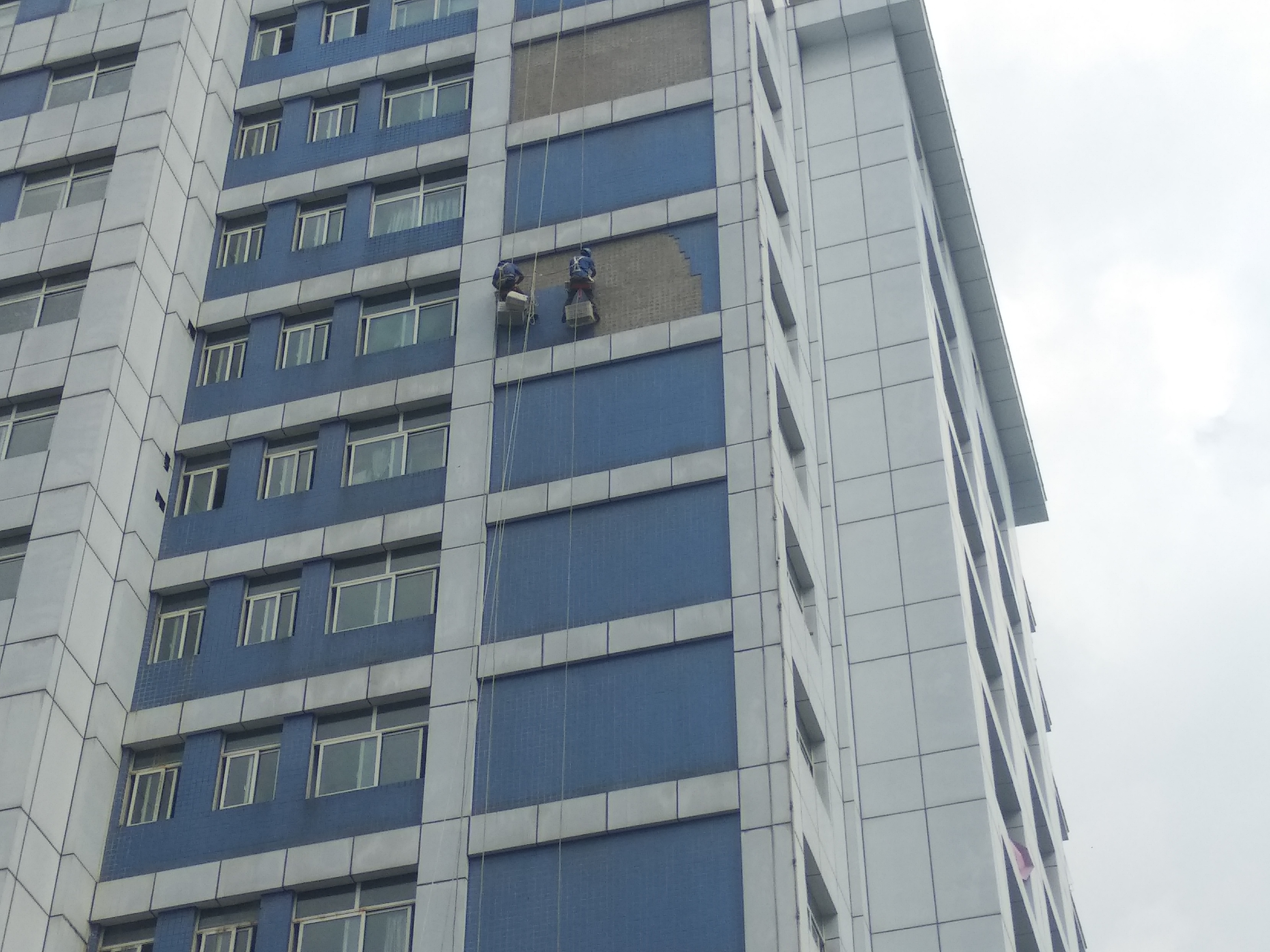 安岳人民医院住院大楼外墙瓷砖脱落,工人师傅正在高空作业剃外墙砖