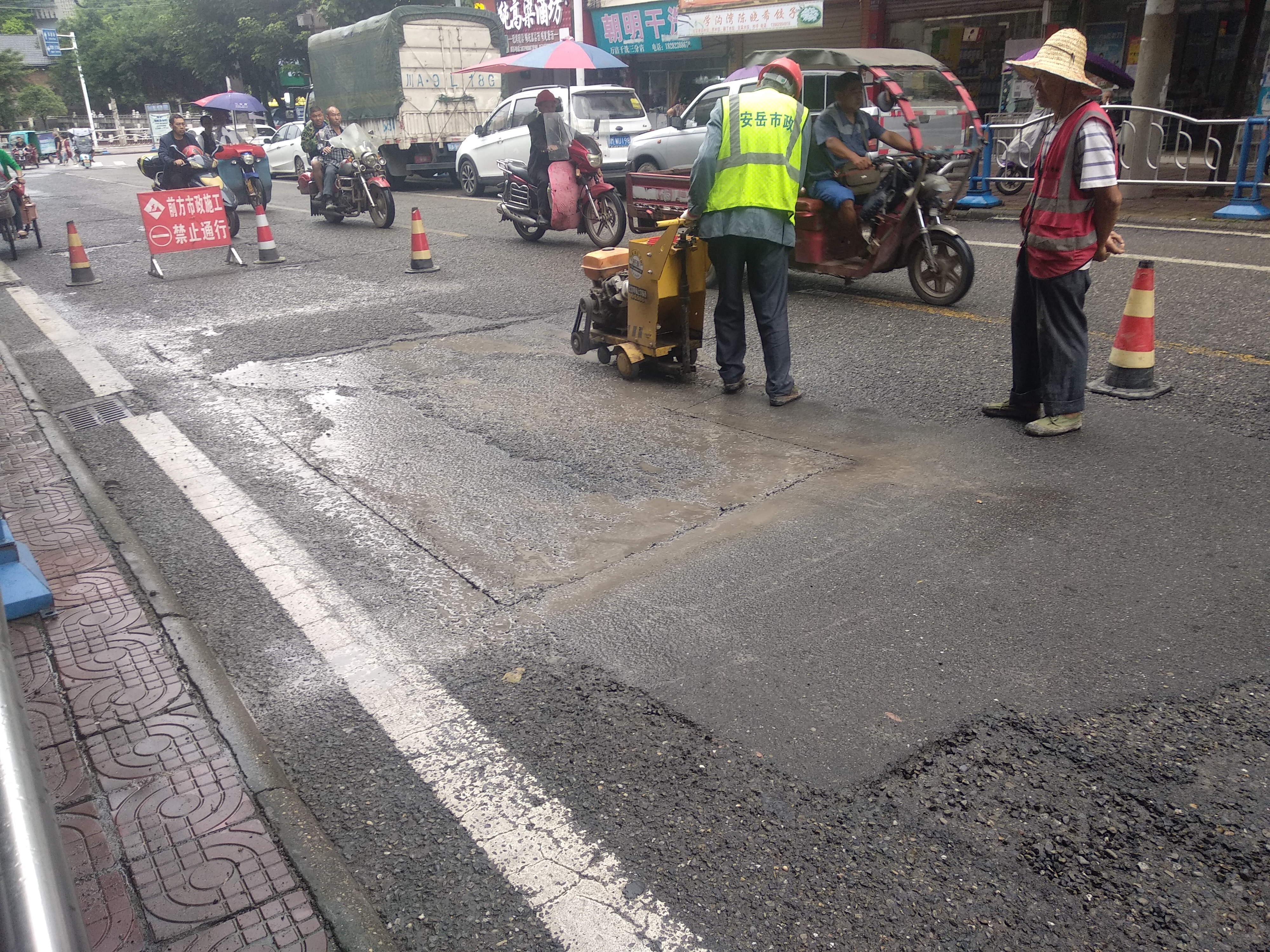 安岳学沟湾路口,工人用机械正在切割凹的沥青路面